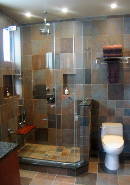 Inspiration for a mid-sized modern master bathroom in New York with flat-panel cabinets, medium wood cabinets, an open shower, a one-piece toilet, multi-coloured tile, porcelain tile, multi-coloured walls, porcelain floors, granite benchtops, multi-coloured floor, a hinged shower door, black benchtops, an undermount sink, a niche, a single vanity, a floating vanity and vaulted.
