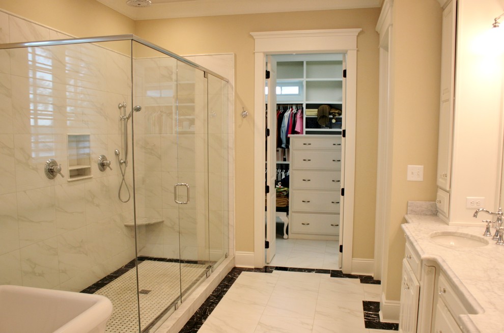 Inspiration for a master bathroom in Other with an undermount sink, raised-panel cabinets, white cabinets, marble benchtops, a freestanding tub, a double shower, a one-piece toilet, white tile, beige walls and ceramic floors.