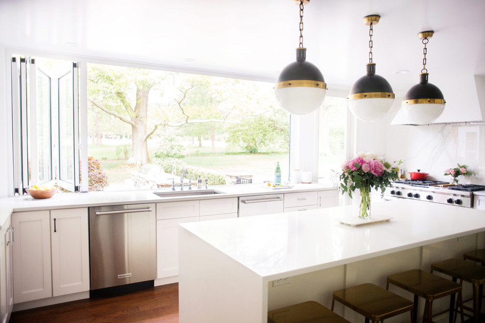 Inspiration for a transitional dark wood floor and brown floor enclosed kitchen remodel with an undermount sink, shaker cabinets, white cabinets, quartz countertops, white backsplash, stone slab backsplash, stainless steel appliances and an island