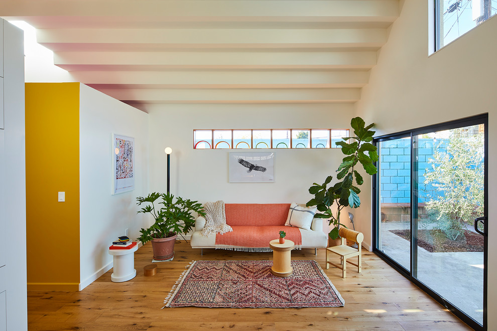 This is an example of a midcentury open concept living room in Los Angeles with white walls, medium hardwood floors and no fireplace.
