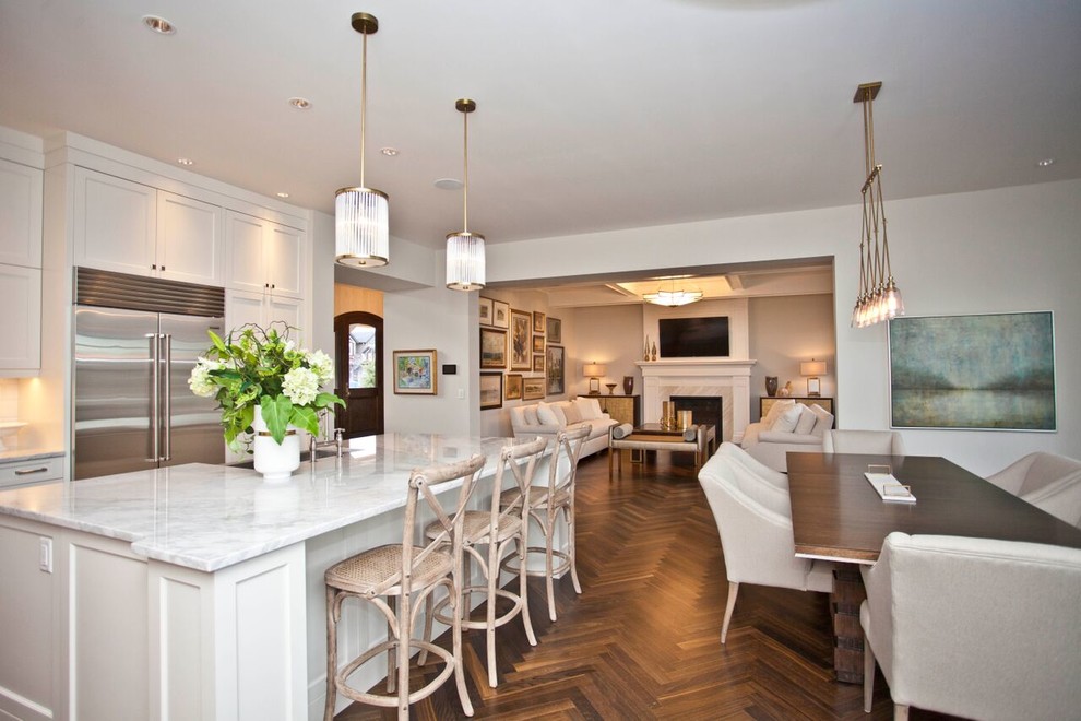 Inspiration for a large transitional l-shaped medium tone wood floor open concept kitchen remodel in Calgary with shaker cabinets, white cabinets, marble countertops, stainless steel appliances and an island
