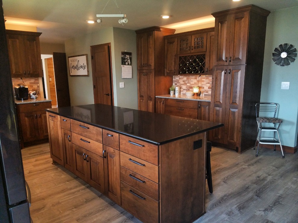Mid-sized traditional l-shaped eat-in kitchen in Minneapolis with an undermount sink, raised-panel cabinets, medium wood cabinets, quartz benchtops, metallic splashback, mosaic tile splashback, stainless steel appliances, vinyl floors, with island and multi-coloured floor.
