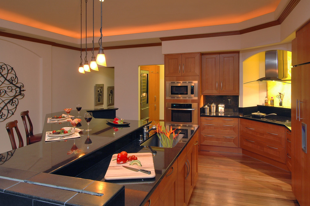 Photo of a traditional kitchen in Hawaii with a single-bowl sink, shaker cabinets, medium wood cabinets, black splashback and panelled appliances.