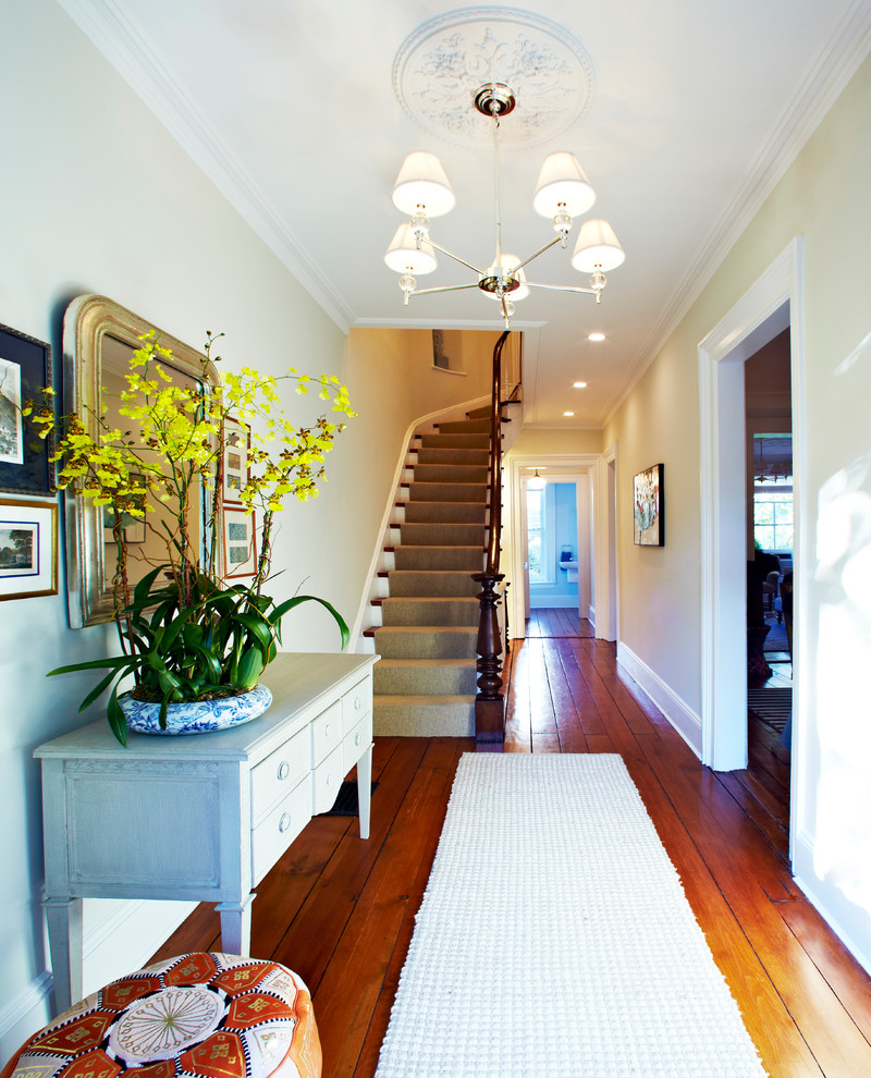 Large traditional entry hall in New York with beige walls, medium hardwood floors and a single front door.