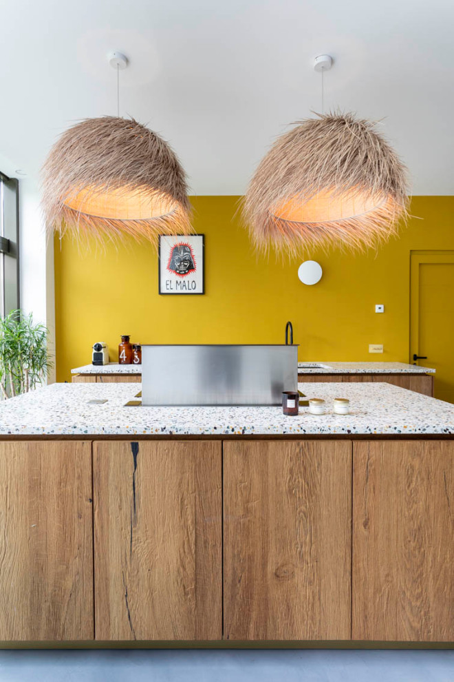 Inspiration for a large galley open plan kitchen in Paris with an undermount sink, beaded inset cabinets, dark wood cabinets, terrazzo benchtops, yellow splashback, panelled appliances, concrete floors, with island, grey floor and white benchtop.