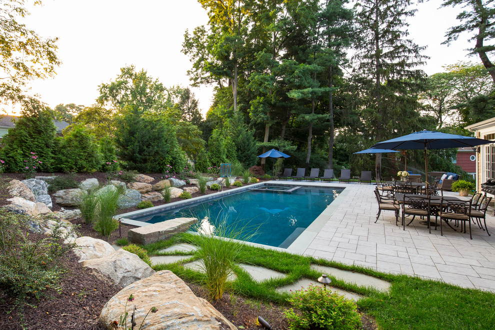 Inspiration for a large traditional backyard rectangular lap pool in New York with a hot tub and natural stone pavers.