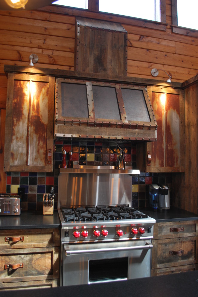 Example of a large mountain style l-shaped eat-in kitchen design in Richmond with shaker cabinets, distressed cabinets, soapstone countertops, an island, multicolored backsplash, glass tile backsplash and stainless steel appliances