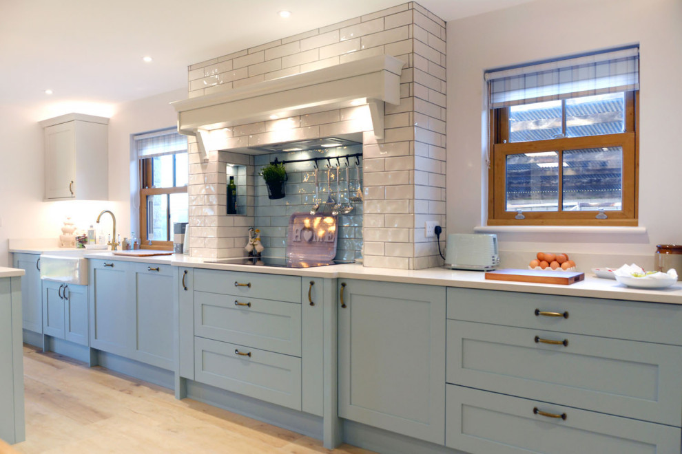 Inspiration for a mid-sized beach style galley open plan kitchen in Cornwall with shaker cabinets, blue cabinets, quartzite benchtops, subway tile splashback, with island and white benchtop.