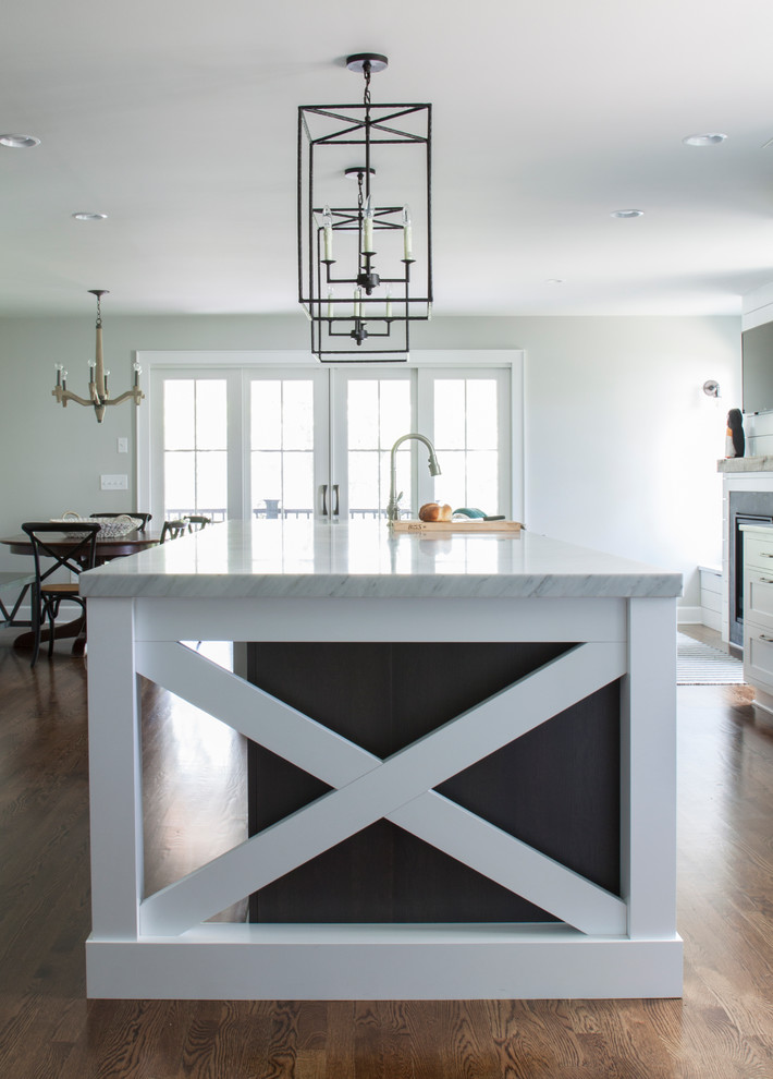 Inspiration for a large transitional l-shaped dark wood floor enclosed kitchen remodel in Newark with a farmhouse sink, shaker cabinets, white cabinets, marble countertops, white backsplash, stainless steel appliances and an island