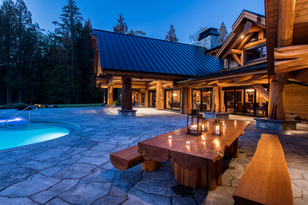Expansive country backyard kidney-shaped aboveground pool in Other with concrete pavers and a hot tub.