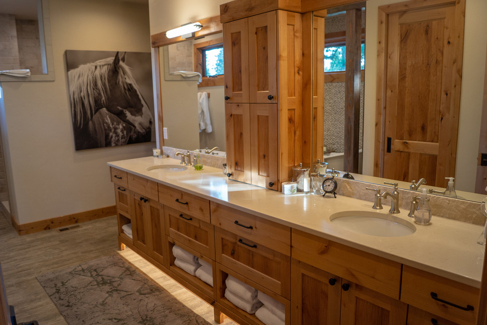 This is an example of a large country master bathroom in Other with shaker cabinets, distressed cabinets, a freestanding tub, a two-piece toilet, brown tile, ceramic tile, brown walls, ceramic floors, an undermount sink, engineered quartz benchtops, brown floor, an open shower and beige benchtops.
