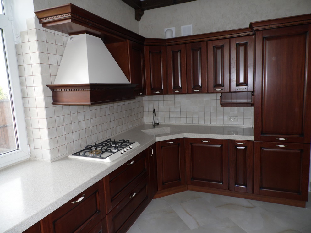 Inspiration for a large traditional l-shaped separate kitchen in Other with an integrated sink, raised-panel cabinets, medium wood cabinets, solid surface benchtops, beige splashback, ceramic splashback, white appliances, laminate floors, a peninsula, grey floor and beige benchtop.