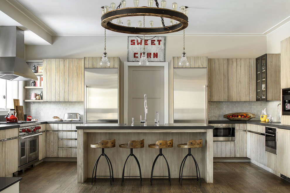 This is an example of a country u-shaped kitchen in New York with a farmhouse sink, light wood cabinets, grey splashback, stainless steel appliances, dark hardwood floors, with island and brown floor.