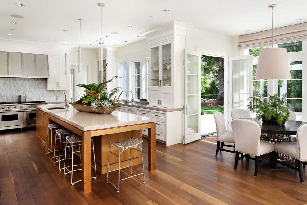 Photo of a traditional u-shaped eat-in kitchen in San Francisco with an undermount sink, shaker cabinets, white cabinets, stainless steel appliances, dark hardwood floors and with island.