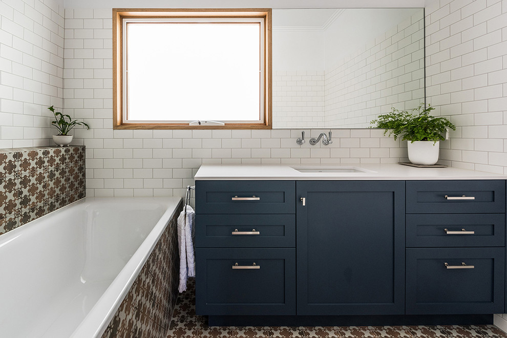 Design ideas for a mid-sized contemporary master bathroom in Melbourne with shaker cabinets, blue cabinets, a drop-in tub, a one-piece toilet, white tile, porcelain tile, white walls, porcelain floors, an undermount sink, engineered quartz benchtops and brown floor.