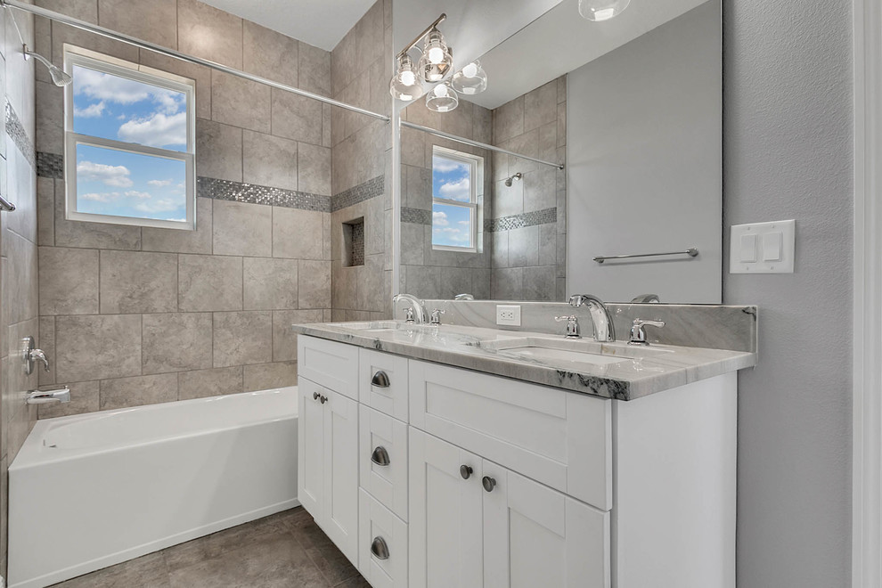 This is an example of a large country master bathroom in Orlando with shaker cabinets, white cabinets, a drop-in tub, a shower/bathtub combo, a one-piece toilet, gray tile, mirror tile, grey walls, porcelain floors, an undermount sink, engineered quartz benchtops, grey floor, an open shower and grey benchtops.
