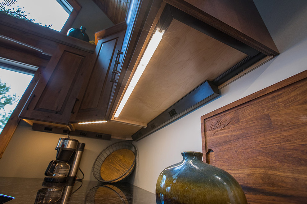 Kitchen - rustic kitchen idea with raised-panel cabinets, distressed cabinets and black countertops