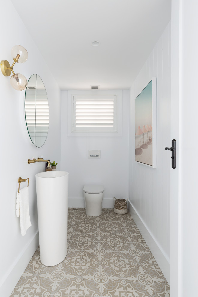 Design ideas for a mid-sized beach style bathroom in Sydney with white cabinets, a wall-mount toilet, white walls, ceramic floors, a pedestal sink, beige floor, an enclosed toilet, a single vanity, a freestanding vanity and planked wall panelling.