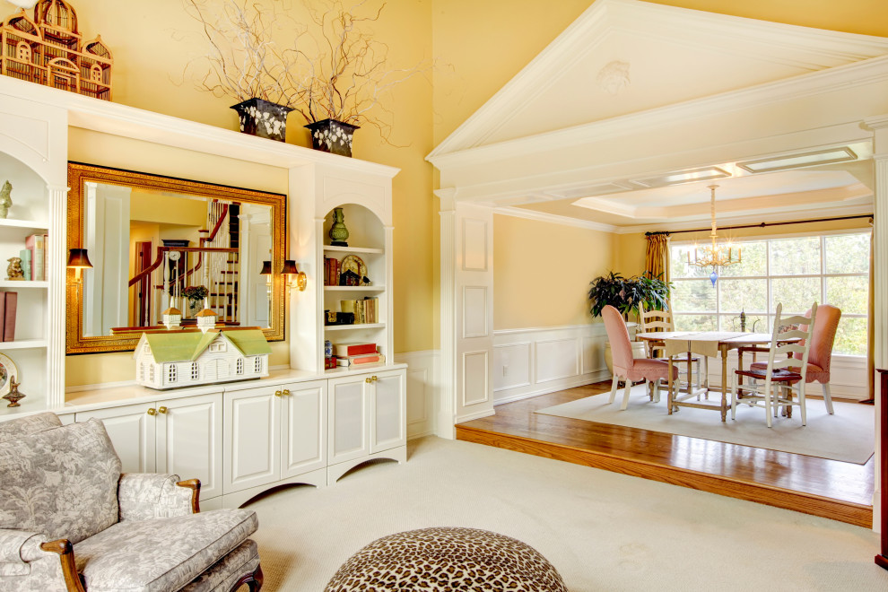 Medium sized victorian grey and yellow open plan living room in London with a reading nook, beige walls, carpet, no fireplace, a plastered fireplace surround, a freestanding tv, beige floors, a drop ceiling, wainscoting and feature lighting.