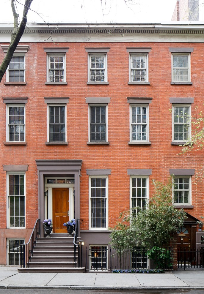 This is an example of a traditional three-storey brick red townhouse exterior in New York with a flat roof.