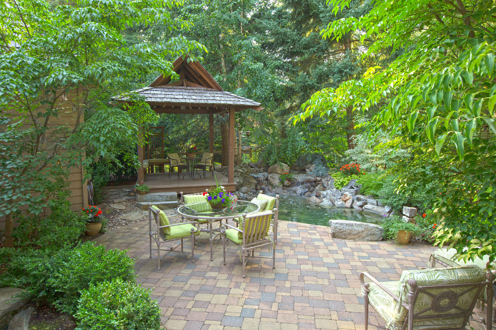 Photo of a traditional patio in Seattle with brick pavers, a gazebo/cabana and a water feature.