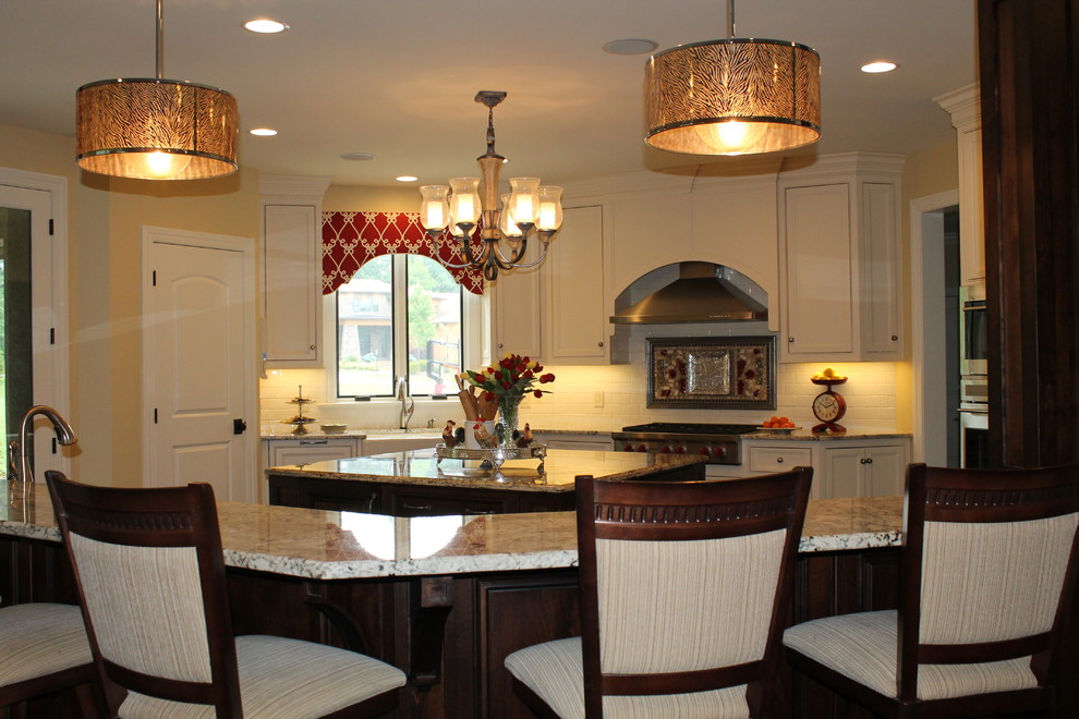 Example of a large transitional u-shaped dark wood floor eat-in kitchen design in Cleveland with a farmhouse sink, recessed-panel cabinets, white cabinets, granite countertops, white backsplash, ceramic backsplash, stainless steel appliances and two islands