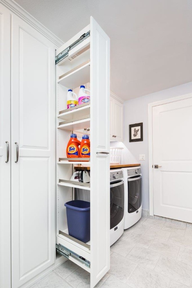 This is an example of a mid-sized traditional galley utility room in San Francisco with white cabinets, wood benchtops, a side-by-side washer and dryer, raised-panel cabinets and grey walls.