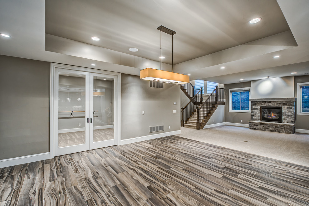 Basement - huge transitional vinyl floor basement idea in Denver with gray walls, a standard fireplace and a stone fireplace