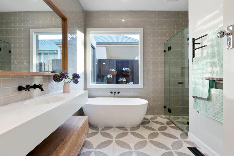 This is an example of a large contemporary master bathroom in Melbourne with furniture-like cabinets, white cabinets, a freestanding tub, a double shower, white tile, ceramic tile, grey walls, ceramic floors, an integrated sink, soapstone benchtops and grey floor.