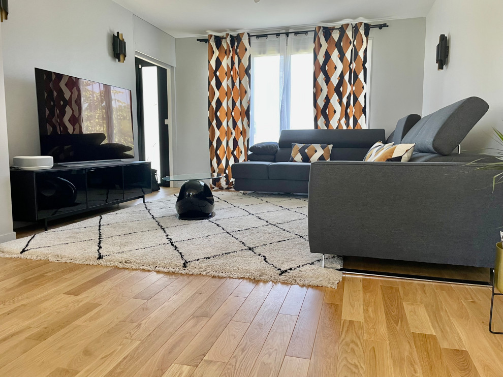 Mittelgroßes Industrial Wohnzimmer ohne Kamin mit grauer Wandfarbe, hellem Holzboden, freistehendem TV und braunem Boden in Paris