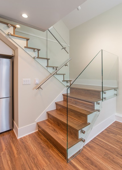 Photo of a mid-sized midcentury wood u-shaped staircase in Vancouver with wood risers and glass railing.