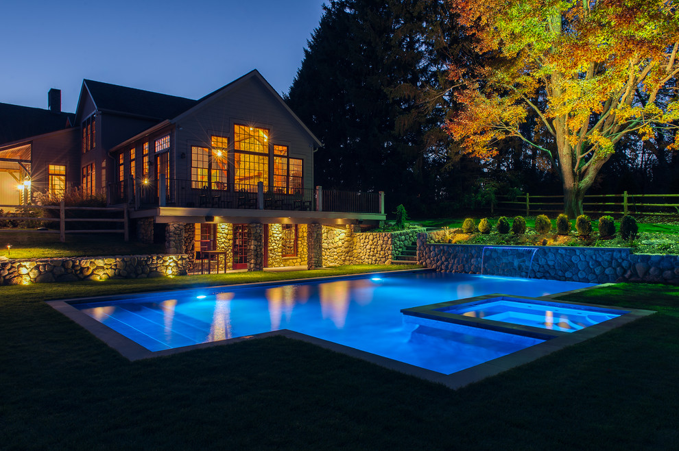 Mid-sized contemporary backyard custom-shaped pool in New York with a water feature and natural stone pavers.