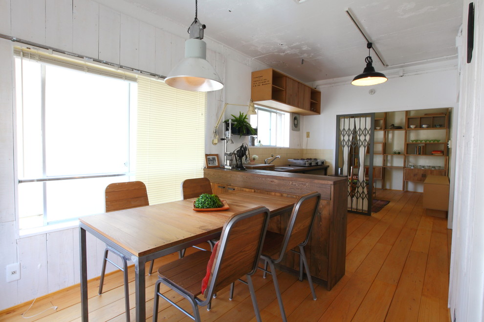 Small industrial kitchen/dining combo in Nagoya with white walls, medium hardwood floors and brown floor.