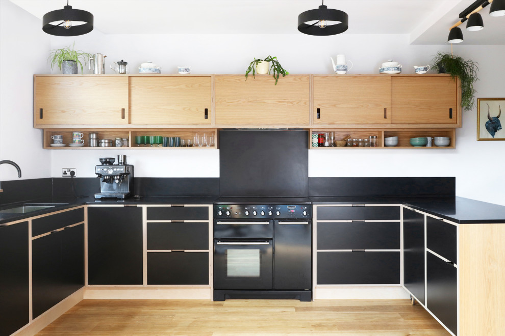 Photo of a medium sized scandinavian u-shaped kitchen in Manchester with flat-panel cabinets, light wood cabinets, engineered stone countertops and black worktops.