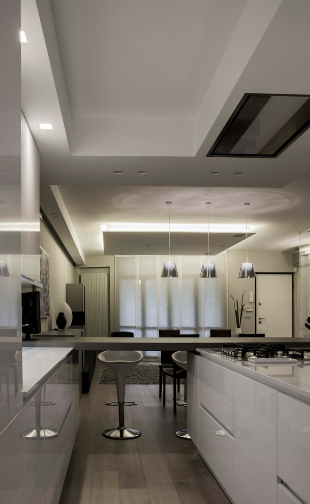 Inspiration for a mid-sized modern u-shaped open plan kitchen in Turin with an integrated sink, white cabinets, granite benchtops, marble splashback, stainless steel appliances, light hardwood floors, with island and brown floor.
