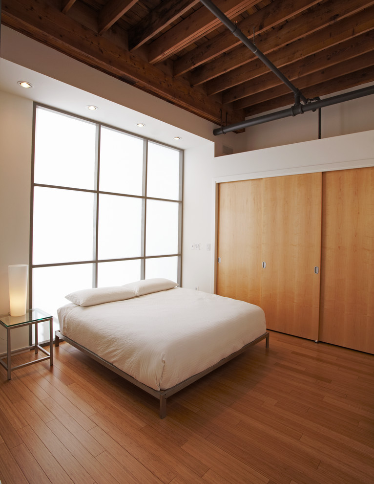 Modern loft-style bedroom in Chicago with white walls and bamboo floors.