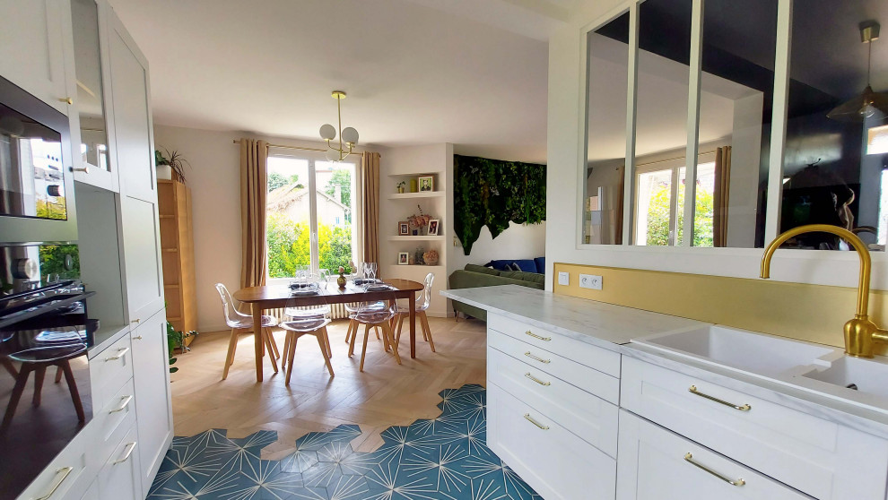 This is an example of a large midcentury u-shaped open plan kitchen in Paris with a drop-in sink, white cabinets, laminate benchtops, metallic splashback, black appliances, cement tiles, no island, blue floor and white benchtop.