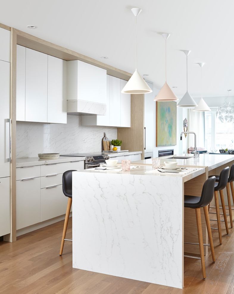 Inspiration for a mid-sized contemporary galley eat-in kitchen in Toronto with an undermount sink, flat-panel cabinets, white cabinets, quartz benchtops, grey splashback, stone slab splashback, panelled appliances, medium hardwood floors, with island, brown floor and grey benchtop.