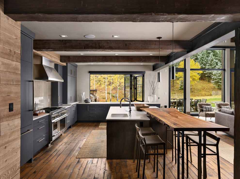 Design ideas for a country l-shaped open plan kitchen in Denver with an undermount sink, flat-panel cabinets, grey cabinets, beige splashback, stainless steel appliances, dark hardwood floors and white benchtop.
