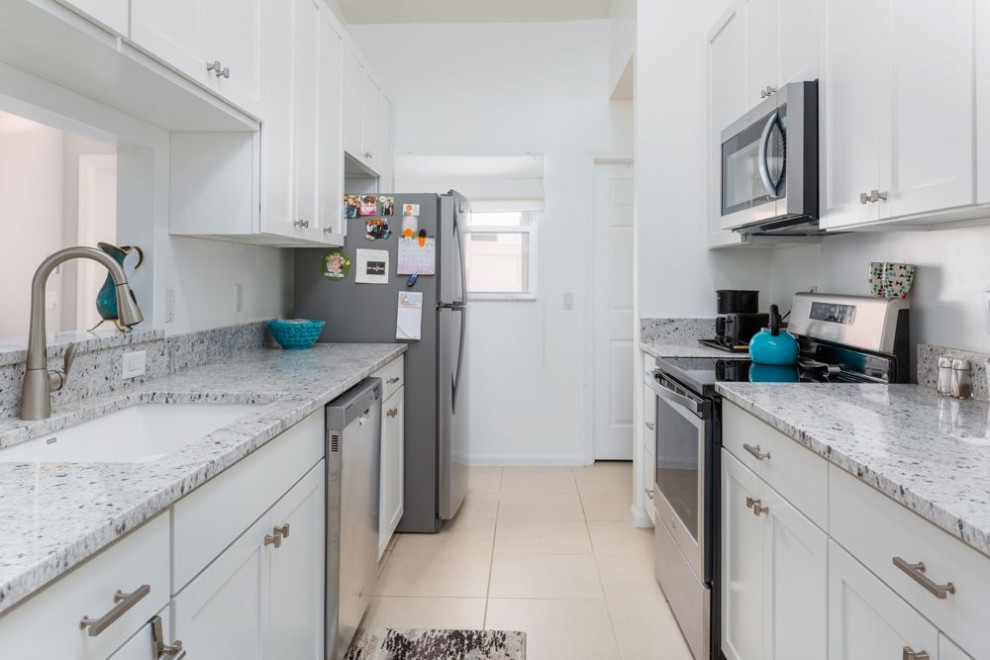 Inspiration for a small classic galley enclosed kitchen in Miami with a built-in sink, shaker cabinets, white cabinets, granite worktops, white splashback, granite splashback, stainless steel appliances, ceramic flooring, no island, beige floors and yellow worktops.