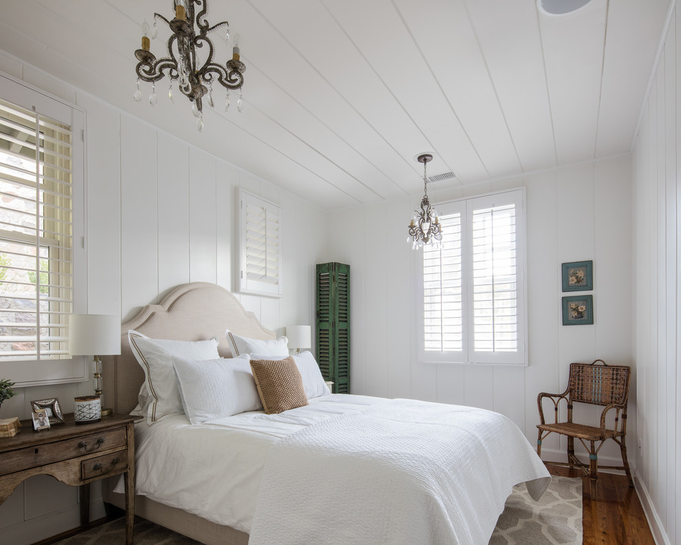 This is an example of a bedroom in Los Angeles with white walls, medium hardwood floors and no fireplace.