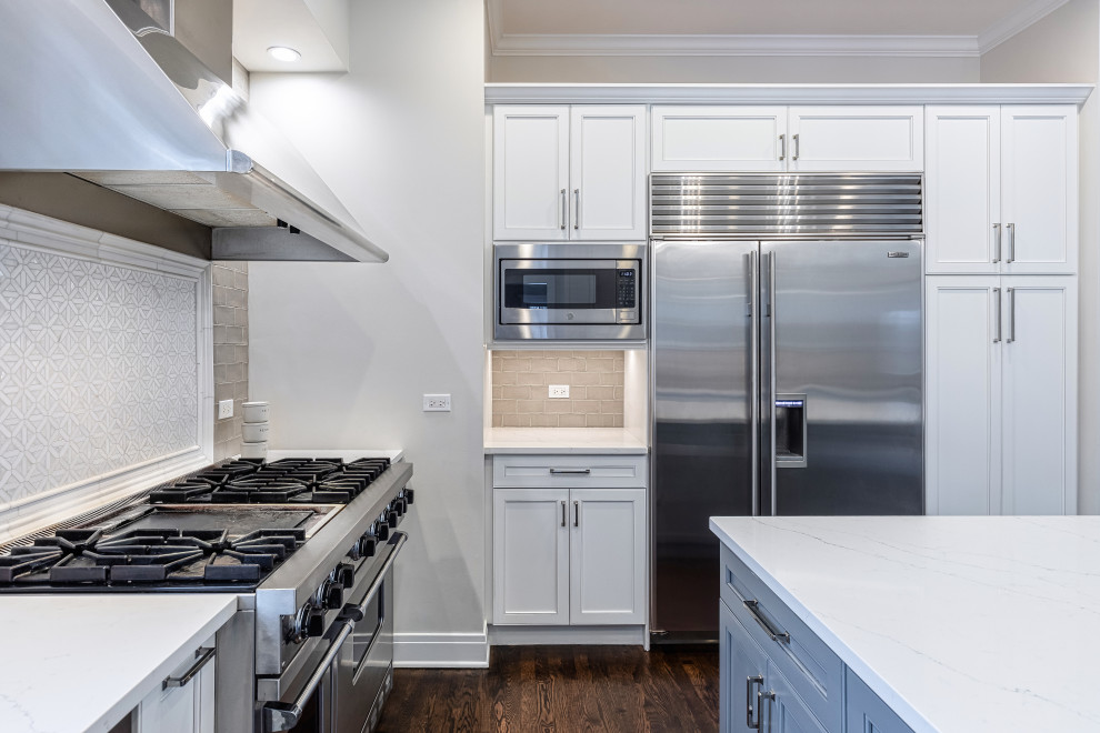 Eat-in kitchen - large transitional u-shaped dark wood floor and brown floor eat-in kitchen idea in Chicago with a farmhouse sink, beaded inset cabinets, white cabinets, quartz countertops, gray backsplash, glass tile backsplash, stainless steel appliances, an island and white countertops