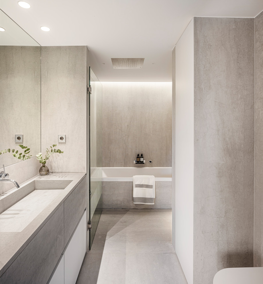Idéer för att renovera ett mellanstort funkis grå grått en-suite badrum, med möbel-liknande, grå skåp, ett platsbyggt badkar, en öppen dusch, en vägghängd toalettstol, grå kakel, stenhäll, grå väggar, kalkstensgolv, ett nedsänkt handfat, bänkskiva i betong, grått golv och dusch med gångjärnsdörr