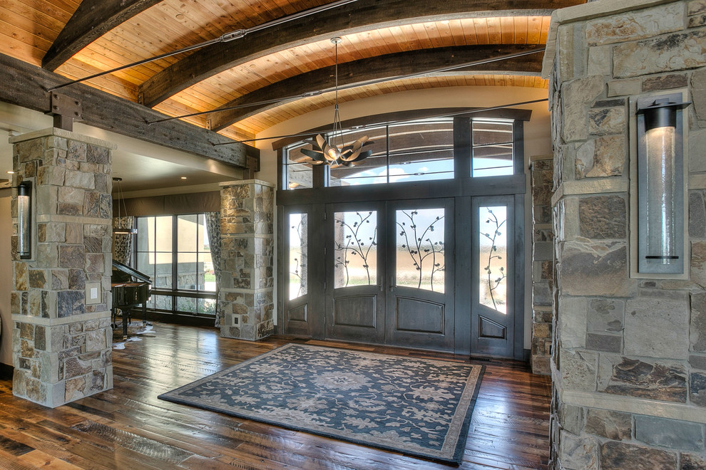 Example of a huge mountain style medium tone wood floor front door design in Denver with beige walls and a dark wood front door