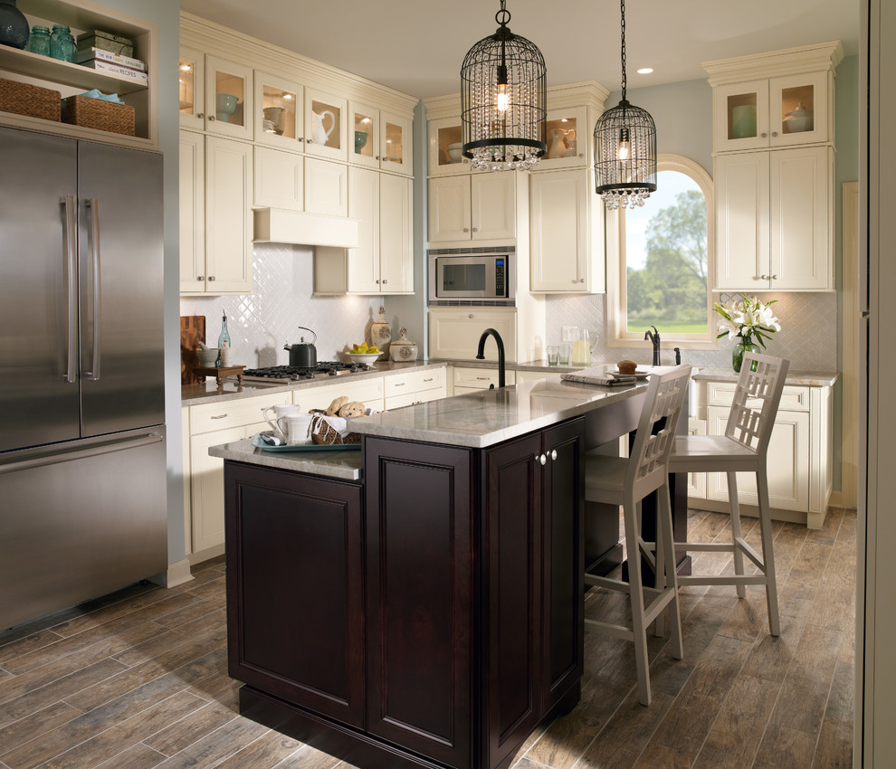 Enclosed kitchen - mid-sized transitional u-shaped medium tone wood floor and brown floor enclosed kitchen idea with a farmhouse sink, recessed-panel cabinets, white cabinets, quartzite countertops, gray backsplash, porcelain backsplash, stainless steel appliances and an island