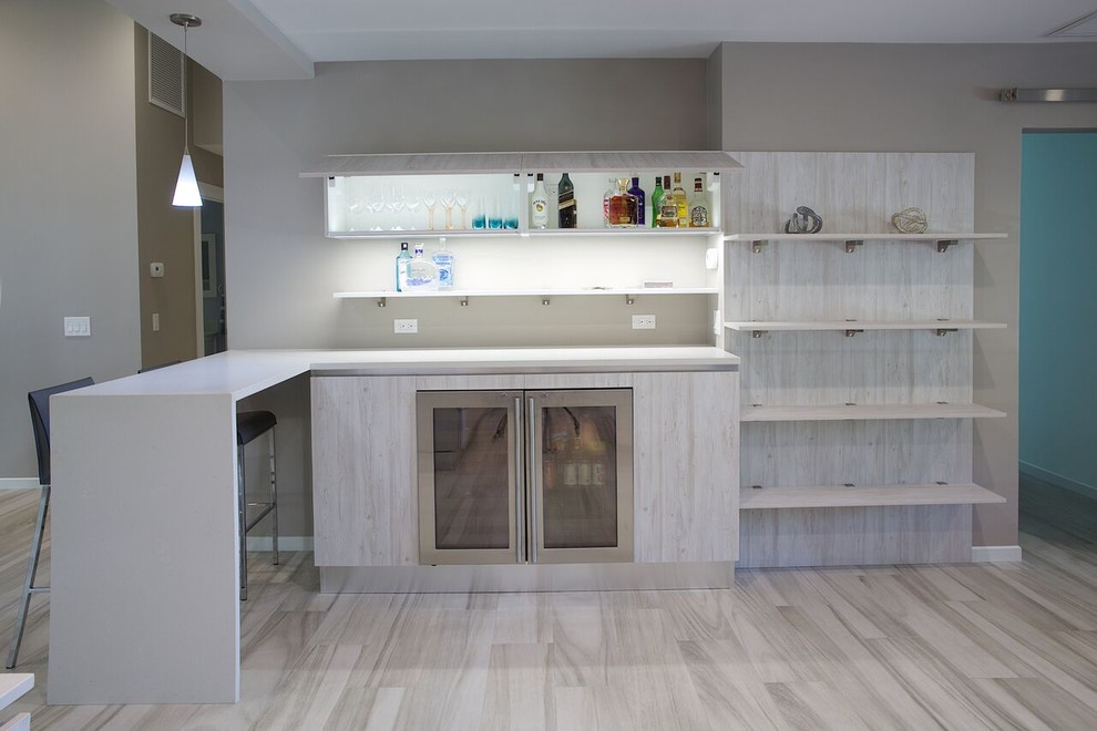 Inspiration for a mid-sized beach style eat-in kitchen in Miami with flat-panel cabinets, light wood cabinets, quartz benchtops, grey splashback, stainless steel appliances, porcelain floors and with island.