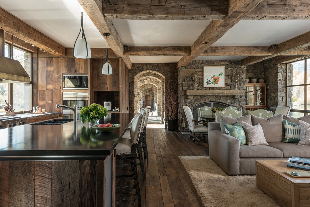 Example of a large mountain style u-shaped dark wood floor open concept kitchen design in Jackson with an island, a double-bowl sink, flat-panel cabinets, dark wood cabinets, solid surface countertops, brown backsplash and stainless steel appliances