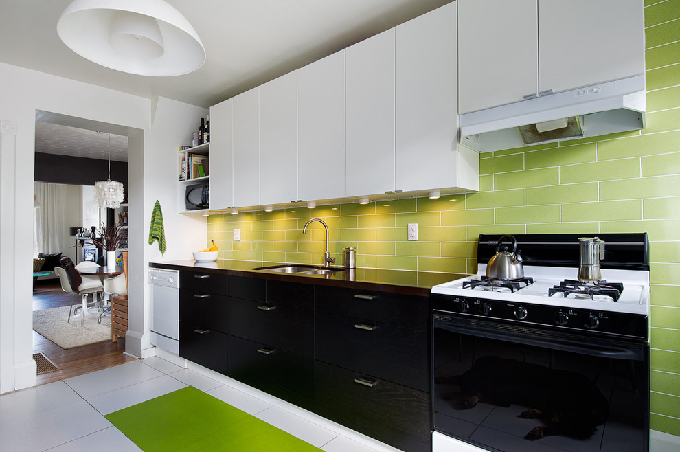 This is an example of a mid-sized contemporary separate kitchen in Toronto with an undermount sink, flat-panel cabinets, black cabinets, quartz benchtops, green splashback, subway tile splashback, white appliances and porcelain floors.