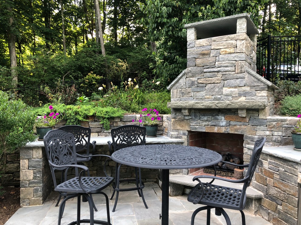Inspiration for a mid-sized country backyard patio in New York with with fireplace and natural stone pavers.