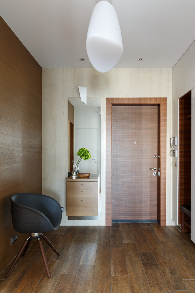Ejemplo de hall contemporáneo de tamaño medio con paredes blancas, suelo de baldosas de porcelana, puerta simple, puerta de madera en tonos medios, suelo marrón y panelado